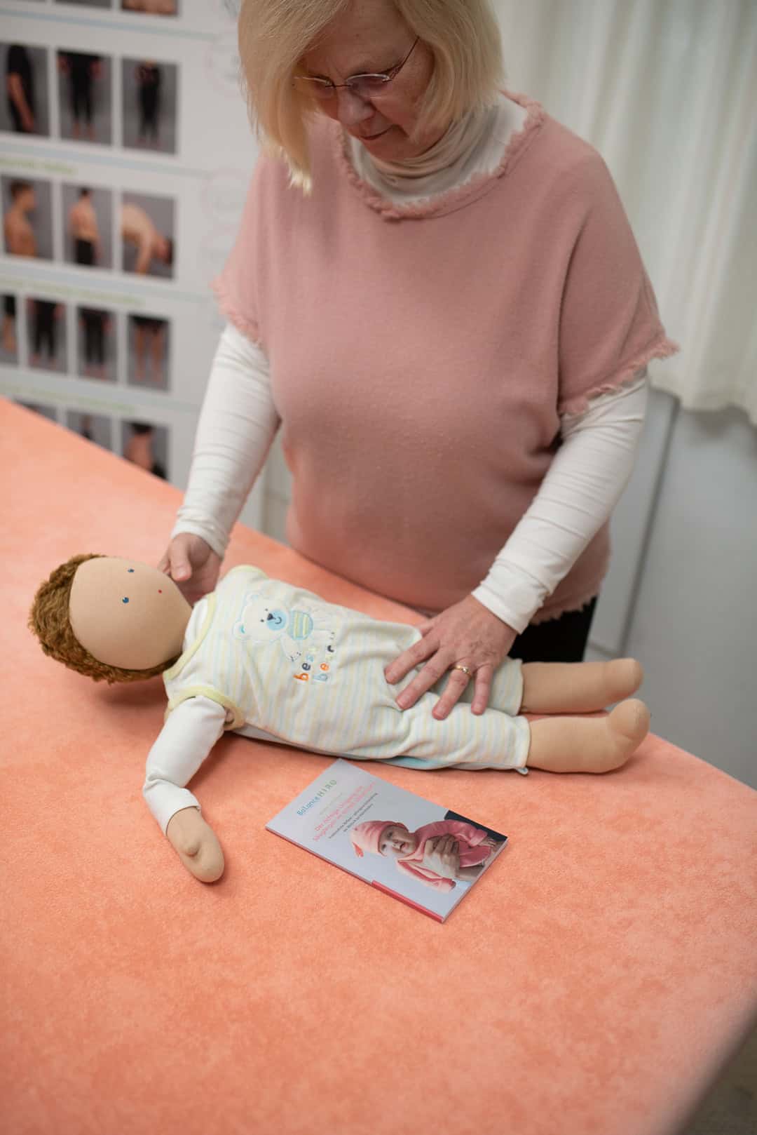 09_eine-frau-in-rosafarbenem-oberteil-massiert-einen-babydummy